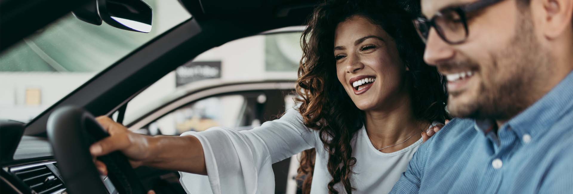 Happy couple enjoying a test drive in a car, emphasizing the excitement of purchasing a vehicle with M&F Bank's auto loans.