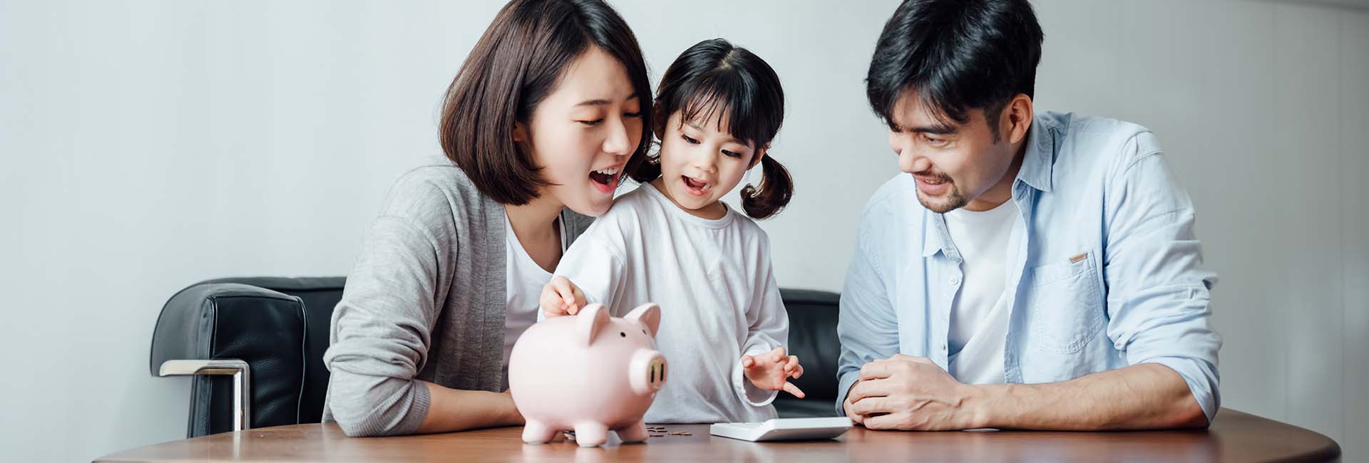 Family engaging in financial education with a piggy bank and tablet, emphasizing smart money habits and financial literacy.