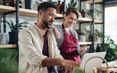 Man and woman collaborating in a modern workspace, discussing financial strategies for small businesses amidst plants and natural light.
