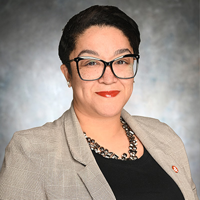 Brittany Adams, Parrish St. Branch Manager at M&F Bank, wearing glasses and a blazer, smiling against a neutral background, representing business banking services.