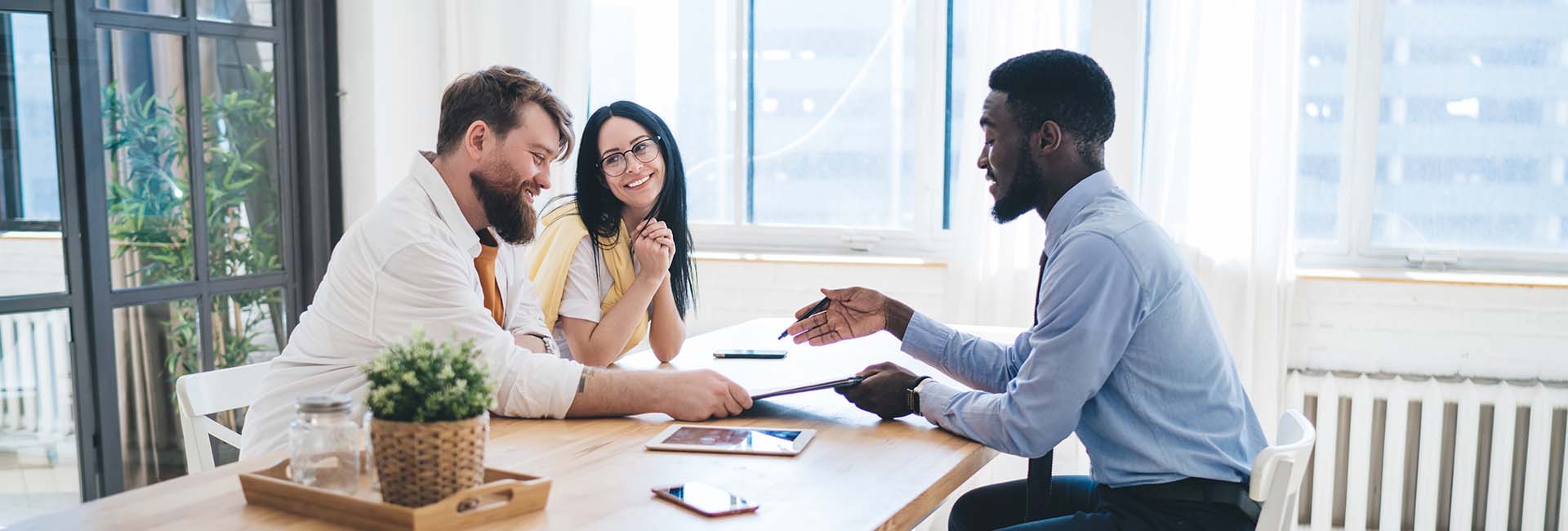 Couple discussing financing options with a bank representative at a table, emphasizing personalized service for SBA loans.