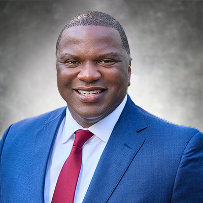 Courtney A. Crowder, member of M&F Bancorp, Inc. Board of Directors, smiling in a blue suit with a red tie.